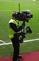 A cameraman pitchside at Tynecastle Stadium