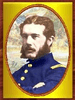 Gold-framed portrait of a white man with brown hair, mustache, and bushy sideburns with his arms crossed. He is wearing a blue military jacket with yellow buttons down the center and a yellow patch on the shoulder.