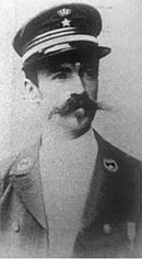 Portrait photograph of a young man wearing a military uniform with a prominent moustache