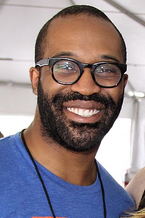 smiling bearded black man wearing glasses and blue T-shirt