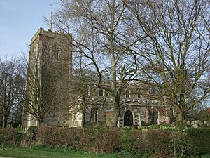 A stone church seen from the south, with a battlemented tower on the left, and a nave with clerestorey and porch to the right