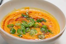 A carrot-ginger soup garnished with green onion and sesame oil