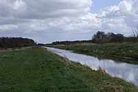 Straight watercourse running between flat grassy fields.