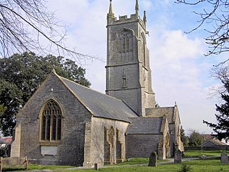 Stone building with prominent square tower. In the foreground are gravestones.