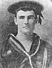 Head and shoulders of a young white man wearing a sailor suit with a star-shaped medal on the left breast and a flat cap with a ribbon tied on the side.