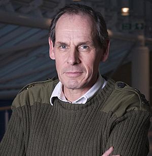 The head and shoulders of a dark-haired man in green jumper