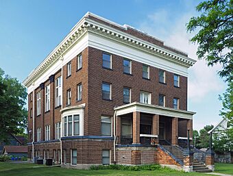 Two-story brick building on a raised basement with a walk-up porch entry