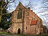 A red brick Gothic Revival church without a tower, but with small gables projections along the edge of the roof