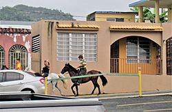 Young man and older man horse-back riding in Ciales barrio-pueblo