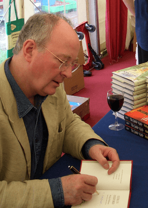 Philip Pullman signing a copy of Lyra's Oxford