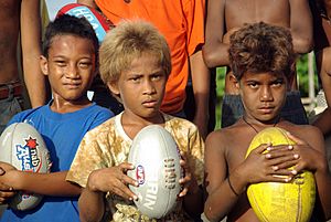 A close up shot of three junior AFL player holding footballs at the Lord Howe Settlement, Honiara. (10661462334)