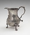 An ornate pewter cream pitcher