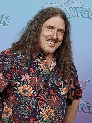 "Weird Al" Yankovic in a multi-colored shirt, against a white background