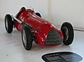 a red vintage open wheel racing car in a museum