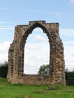 A photograph showing a Gothic arch standing in a field.