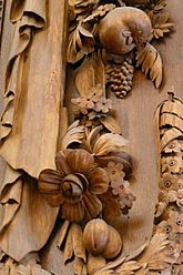 A wreath of flowers, apples, grapes and plums made out of wood.