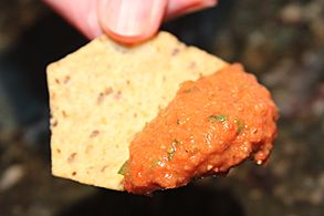A bean dip prepared with white beans and roasted red pepper, on a tortilla chip