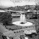 This photograph shows International Fountain in operation. Multiple parabolic arcs can be seen rising from the center of the fountain.