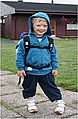 A boy wearing a jacket and a backpack