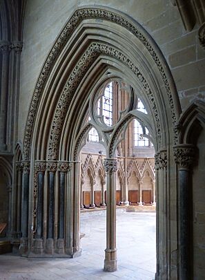 An elegant Gothic doorway opens into a chapter house. The arch of the doorway and the capital of  its central pier have richly carved flowers.