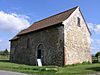A very simple barn-like stone church with a tiled roof