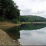 A reservoir surrounded by green forested hillsides.