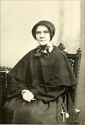 Older white woman, seated, in dark religious habit