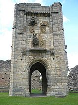 Tall tower with an arched passageway through the bottom. Above the archway are heraldic symbols.