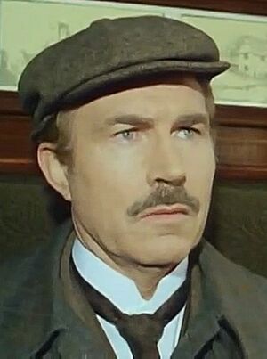 Image of David Burke as Dr. Watson S2.E1 "Copper Beeches" 1985 when he was 51 years of age, sporting a moustache, wearing a tie and a flat cap