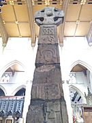 Leeds Cross, panel Ci (south face, top panel). The ornament above the figure is a modern reconstruction. The cross may not originally have belonged to the shaft. The figure is of a holy man.