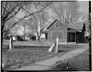 T-SHAPED FRAME HOUSE WITH ROOFED PORCHES. A POST ROCK FENCING IS IN THE FORGROUND - Town of Munjor, Munjor, Ellis County, KS HABS KANS,26-MUNJ,1-3