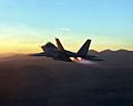 Rear view of jet aircraft in-flight at dawn/dusk above mountains. Its engines are in full afterburner, evident through the presence of shock diamonds.