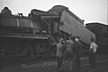 Railway workers looking at the damaged train tender after a crash at Tamaree, October 1947