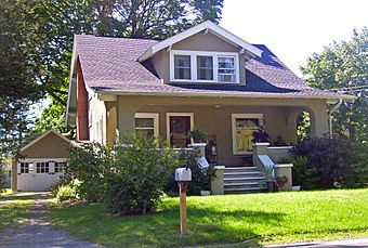 A brown house with small front lawn and garage to the rear on the left