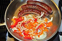 Sausages cooking with peppers and onion