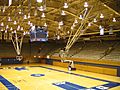 Interior of basketball stadium showcasing court, rafters, and empty stands