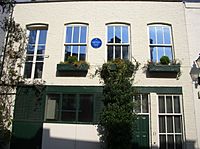 exterior of cream painted mews house, with blue plaque on front wall