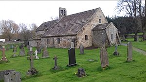 A small stone church with graves in the foreground