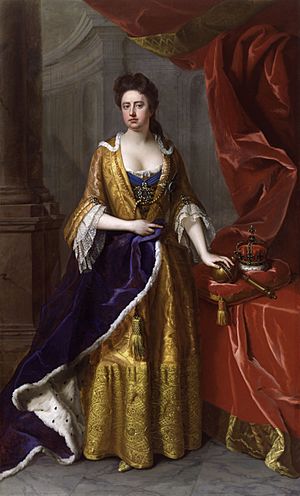 Anne in blue and yellow robes. The Crown Jewels are on a table to her left.