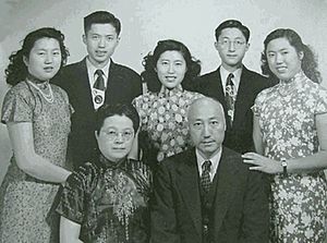 Photograph of a Chinese family showing 5 children standing behind their seated parents.
