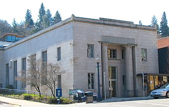 Photograph of a large building on a city street corner with the front entry flanked by two tall pillars