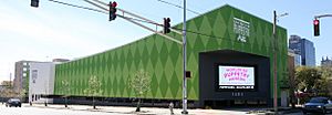 Image features the Center for Puppetry Arts new museum building, which is in a Kermit green harlequin pattern and features a large display screen with the words "Worlds of Puppetry Museum".