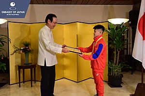 Carlos Yulo receiving an award from Koji Haneda