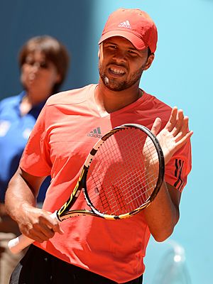 Tsonga in a read shirt looking into the camera.