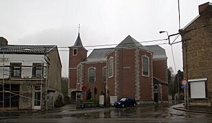 Religious building in brick in Neo-Romanesque style. On the left, a residence.