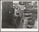 Farm boy sitting on cartons in general store. Jarreau, Louisiana