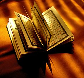 A paper Quran opened halfwise on top of a brown cloth