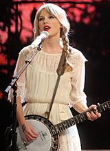 Swift in a white blouse playing a banjitar