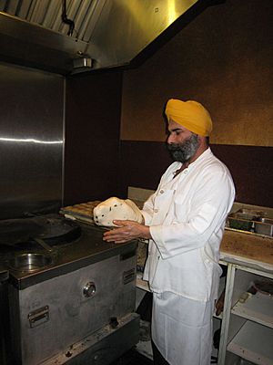 Chef preparing naan to be baked in a tandoori