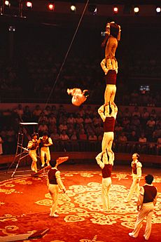 Chinese acrobat in midair being watched by other acrobats